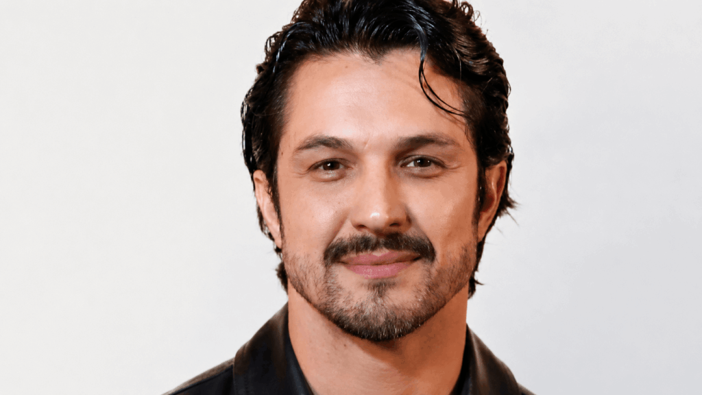 Paulinho sorrindo em foto com fundo clean e visual elegante estilo galã da Globo